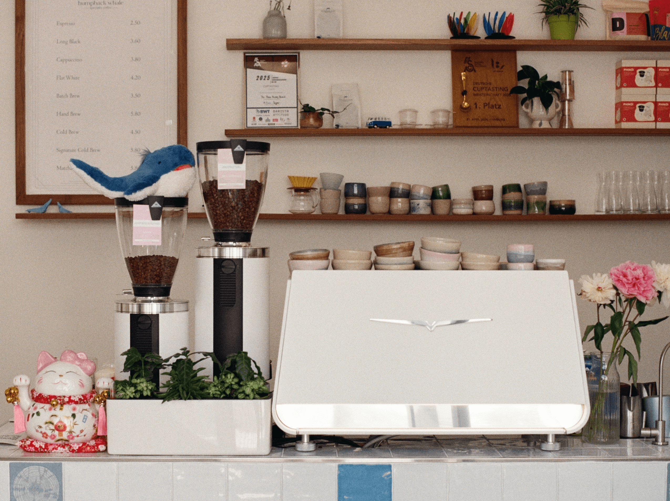 The café bar — espresso machine, handmade ceramic cups, and the 2025 award on the shelf
